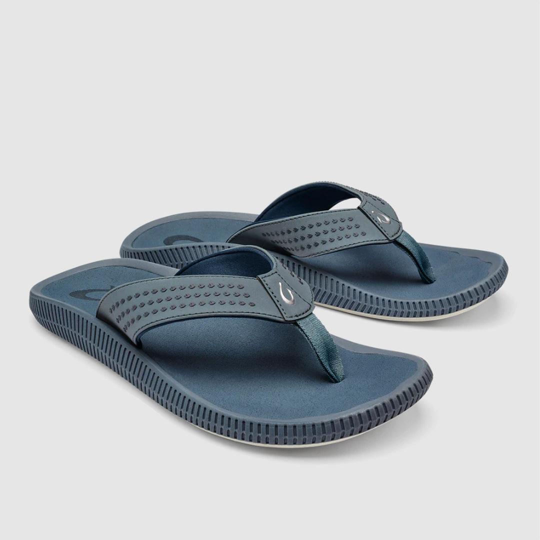 A pair of dark slate blue flip-flop sandals with textured straps and ridged soles, displayed on a light gray background.